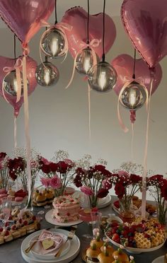 a table topped with lots of heart shaped balloons next to plates filled with desserts