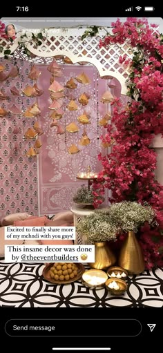 a table topped with lots of flowers next to a wall covered in pink and gold decorations