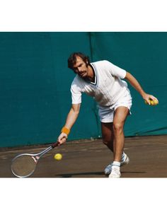 a tennis player in action on the court with his racket and ball behind him