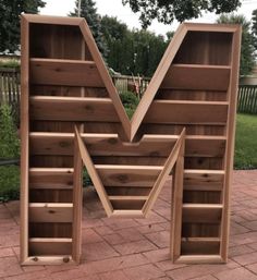 a wooden bookcase with the letter v cut out into it's sides on a brick patio