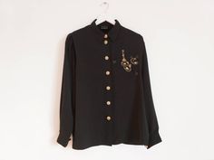 Black vintage blouse with golden decor, Button down blouse, Long sleeve shirt, Embroidered with gold, Embroidered top, black and gold Size L Good vintage condition Label size 40 Measurements (lying flat): Pit to pit 22''/56cm Length 28''/71cm Sleeve length 25'' /63cm Please check measurements to insure a proper fit. Remember to allow yourself some extra room for movement. You can compare measurements with something from your closet that fits you well. Please feel free contact me if you need additional measurements or have any questions! This blouse will come to you freshly laundered and ready to wear. SHIPPING * I ship from Europe (Latvia), so please allow 2 to 4 weeks for the package to arrive if you live overseas. * Europe 1 to 2 weeks. For courier delivery please send Your full phone nu Luxury Black Embroidered Shirt, Elegant Gold Top With Button Closure, Gold Party Tops With Button Closure, Gold Party Top With Button Closure, Gold Tops With Button Closure For Party, Gold Collared Shirt For Work, Embroidered Formal Tops For Fall, Gold Shirt With Buttons For Fall, Gold Long Sleeve Office Blouse