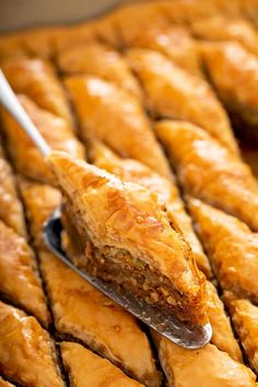 a spoon with some food on it sitting in front of a tray full of pastries