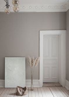 an empty room with a door, mirror and vase on the floor in front of it