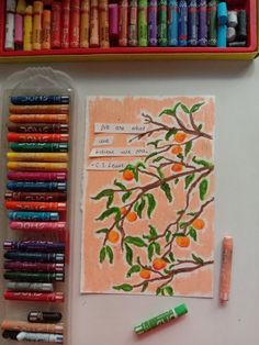 crayons are on the table next to an orange tree with leaves and fruit