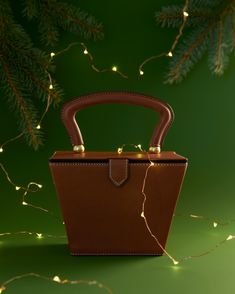 a brown leather purse sitting on top of a green table next to a christmas tree