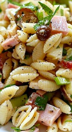 pasta salad with ham, mushrooms and green onions on a white plate in close up