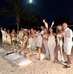 a group of people standing on top of a sandy beach next to a palm tree