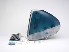 a computer with a keyboard and mouse sitting next to it's back end on a white surface