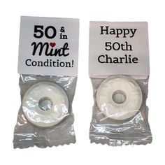 there are two white donuts wrapped in plastic bags with the words happy 50th and 50th charlie on them