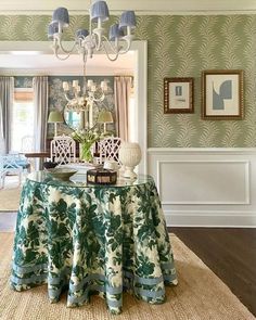 a dining room table covered with a blue and white cloth under a chandelier