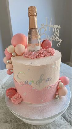 a birthday cake with a bottle of champagne on top and balloons all around the cake