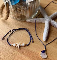 two bracelets on a table next to a starfish and seashell in a jar