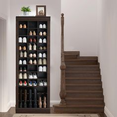 there are many pairs of shoes on the shelf next to the stairs in this room