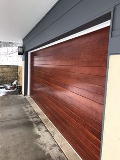 a brown garage door on the side of a building with snow on the ground behind it