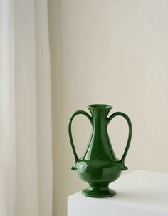 a green vase sitting on top of a white table