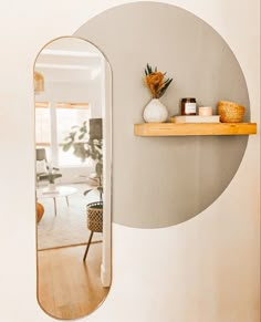 an oval mirror hanging on the wall next to a shelf