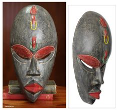 two masks with red and green designs on them, one is made out of wood