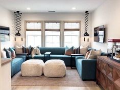 a living room with blue couches and pillows on the floor in front of two windows