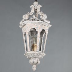 an old fashioned light fixture hanging from a gray ceiling with ornate carvings on the sides