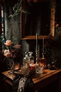 a table with candles, flowers and other items on it in front of a mirror