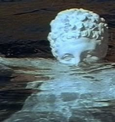 a statue is floating in the water with its head above the water's surface