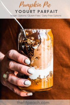 a woman holding a glass jar filled with food and drinking something out of her hand