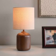 a lamp sitting on top of a white table next to a framed photo and a wooden frame