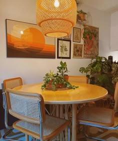 a dining room table with four chairs and a potted plant in the center on top