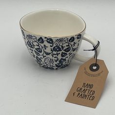 a blue and white coffee cup sitting next to a tag