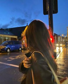 a woman standing on the side of a street next to a traffic light