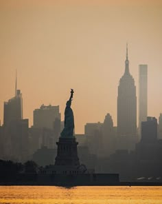 the statue of liberty is silhouetted against an orange and yellow sky in new york city