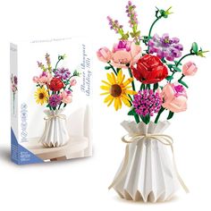 a white vase filled with lots of flowers next to a boxed box on top of a table