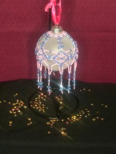 a pink and blue glass ornament sitting on top of a black cloth covered table