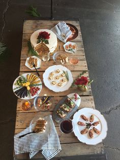 a wooden table topped with lots of plates filled with food and desserts on top of it