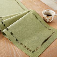 three green napkins on a wooden table with a cup of coffee