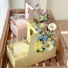 three boxes with flowers in them sitting on a table next to some cookies and cake