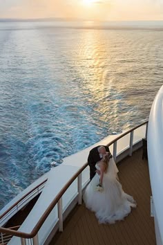 a bride and groom kissing on the deck of a cruise ship as the sun sets