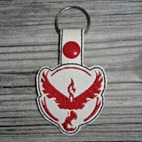 a red and white keychain with a bird on it's back side