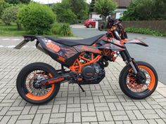 an orange and black dirt bike parked on the street