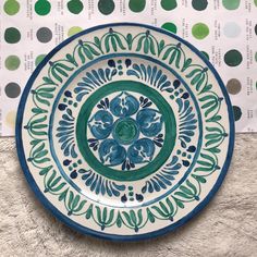 a blue and green plate sitting on top of a white table next to polka dot paper