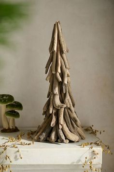 a small tree made out of driftwood sitting on top of a white table next to mushrooms