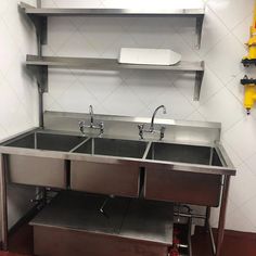 two stainless steel sinks in the middle of a room