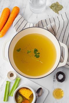 a bowl of soup with carrots and celery next to it on a table