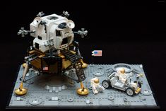 a lego space station with two vehicles on the ground and an american flag in the background