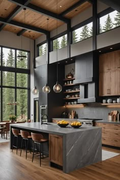 an open kitchen with wooden floors and black walls, along with large windows that look out onto the forest