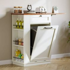 a white cabinet with an open door in a corner next to a plant and clock