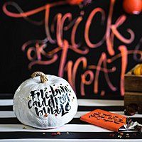 a white pumpkin sitting on top of a table next to candy and other items in front of it