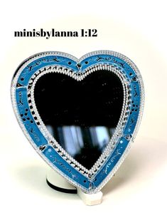 a blue and white heart shaped mirror sitting on top of a stand