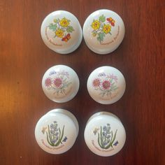 four white plates with flowers painted on them sitting on a table next to each other