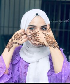 a woman with henna on her hands covering her face